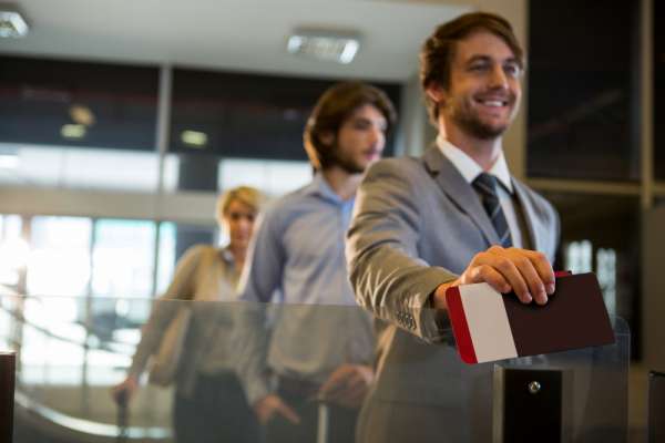 businessman-standing-with-boarding-pass-check-counter